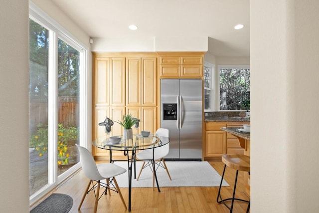 kitchen featuring light hardwood / wood-style floors, light brown cabinets, dark stone counters, and stainless steel fridge with ice dispenser