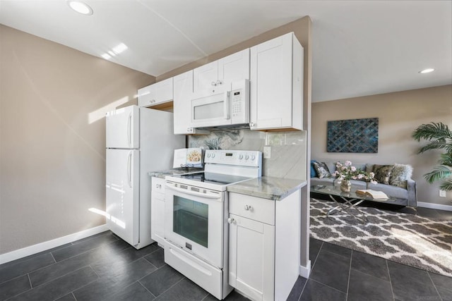 kitchen with dark tile patterned floors, white cabinets, light stone countertops, white appliances, and decorative backsplash