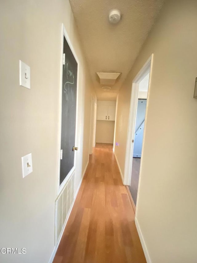 corridor featuring light hardwood / wood-style floors and a textured ceiling