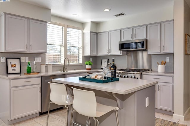 kitchen featuring a center island, light tile patterned floors, sink, a breakfast bar, and stainless steel appliances