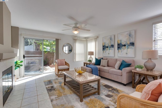 tiled living room with a tile fireplace and ceiling fan