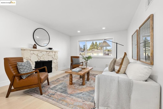 living room featuring hardwood / wood-style floors and a stone fireplace