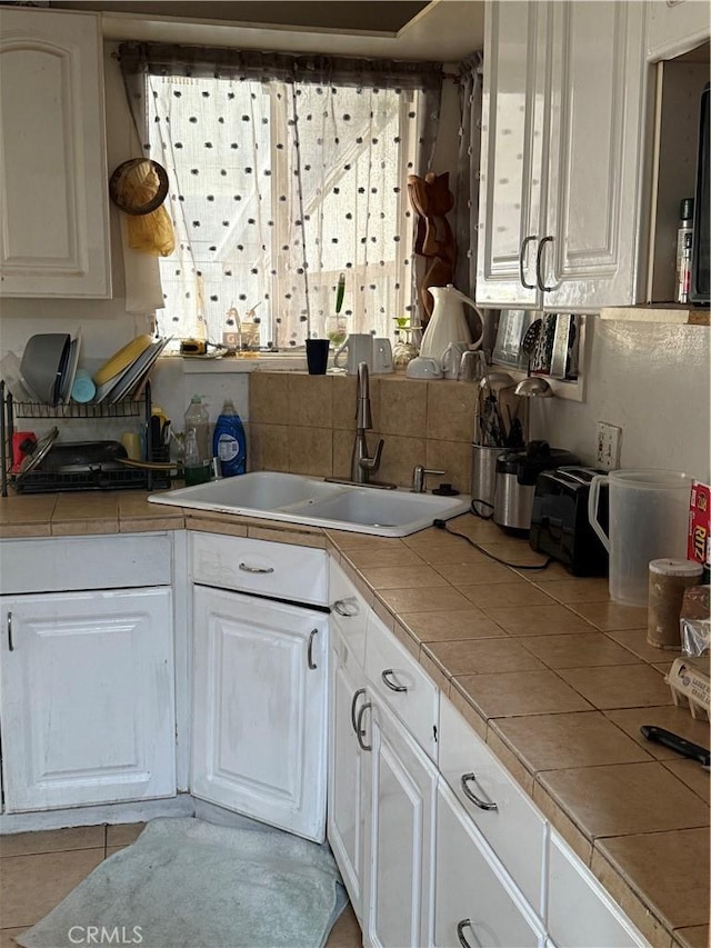 kitchen with sink, white cabinetry, and tile counters