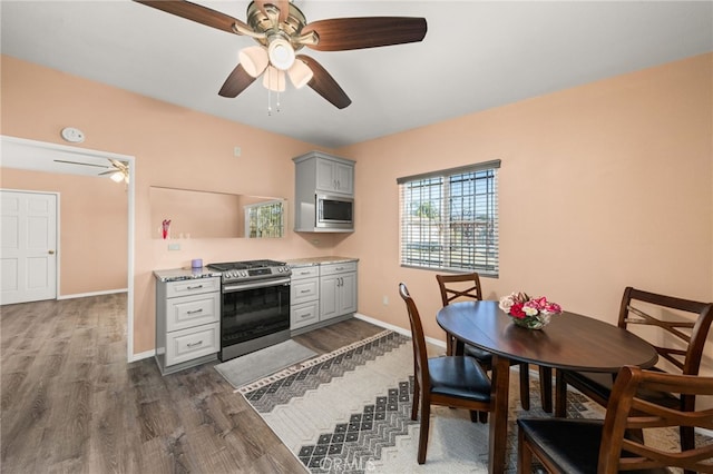 kitchen with gray cabinets, dark wood-type flooring, ceiling fan, and appliances with stainless steel finishes