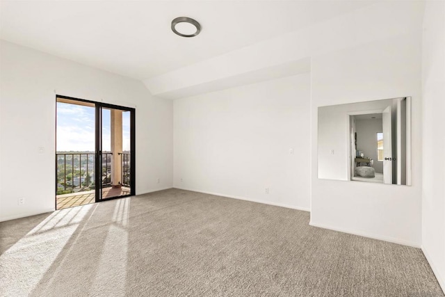 carpeted empty room featuring vaulted ceiling