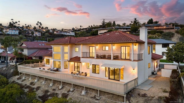 back house at dusk with a balcony and a patio