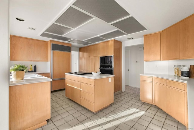 kitchen featuring light brown cabinetry, light tile patterned floors, black appliances, and a center island