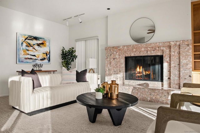 living room featuring track lighting, a fireplace, and carpet flooring