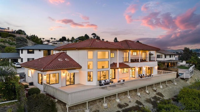 back house at dusk with an outdoor living space and a balcony