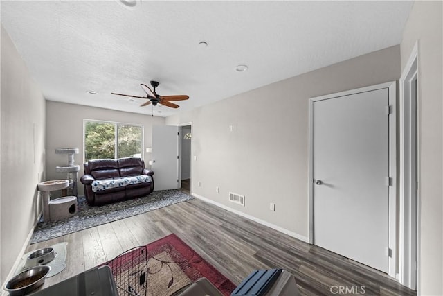 living room with dark hardwood / wood-style flooring, a textured ceiling, and ceiling fan