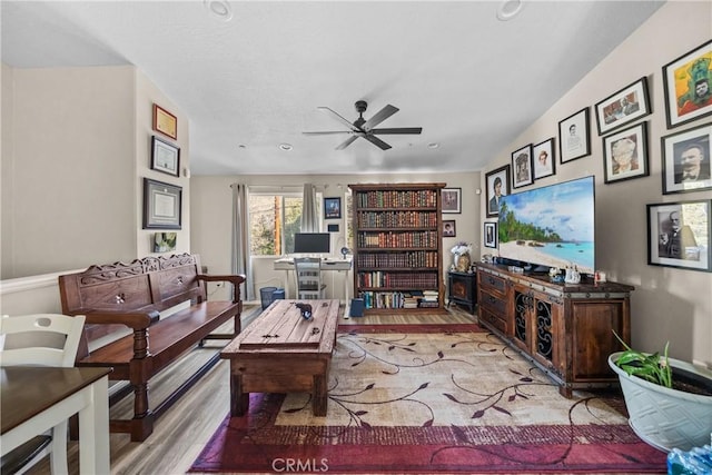 living room featuring ceiling fan, lofted ceiling, and light wood-type flooring