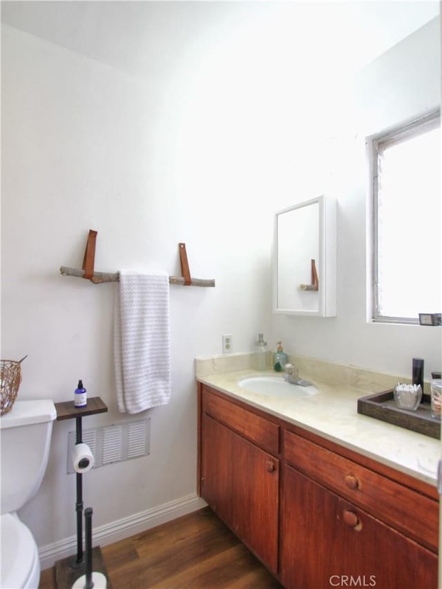 bathroom with vanity, toilet, and hardwood / wood-style flooring