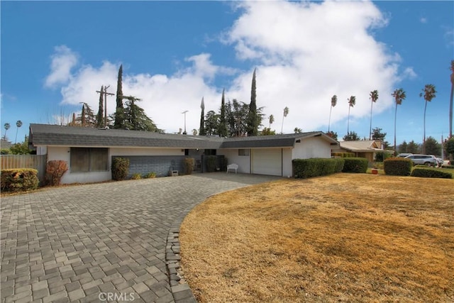 ranch-style house with a garage and a front lawn