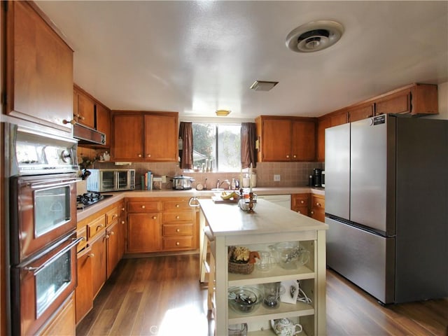 kitchen featuring decorative backsplash, sink, a kitchen island, stainless steel appliances, and dark hardwood / wood-style floors