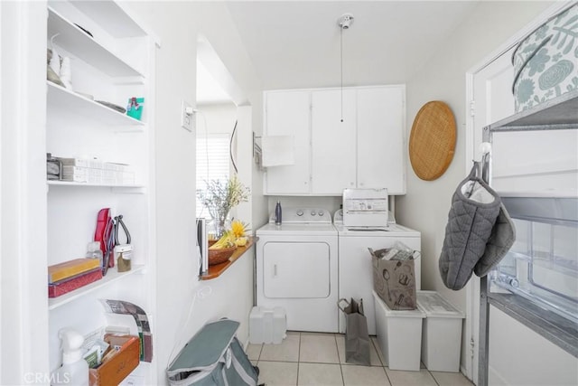 clothes washing area featuring cabinets, light tile patterned floors, and washer and dryer