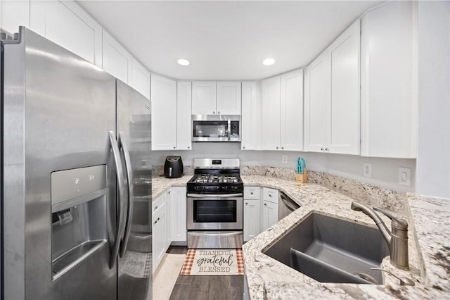 kitchen featuring white cabinetry, sink, light stone countertops, and appliances with stainless steel finishes