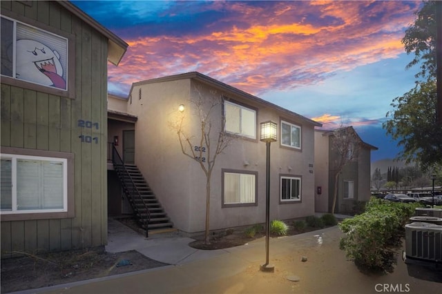 property exterior at dusk with cooling unit and a patio area