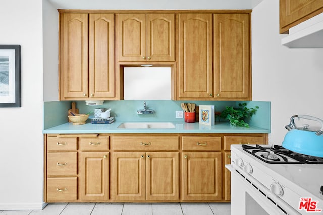 kitchen featuring sink, gas range gas stove, exhaust hood, and light tile patterned floors