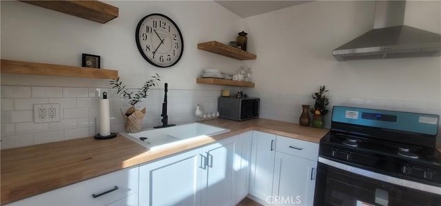 kitchen featuring butcher block countertops, sink, black stove, white cabinets, and wall chimney exhaust hood