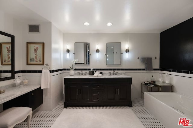 bathroom featuring tile patterned floors, a bathtub, tile walls, and vanity