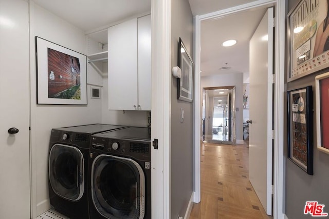 laundry area with cabinets, light parquet flooring, and washer and clothes dryer