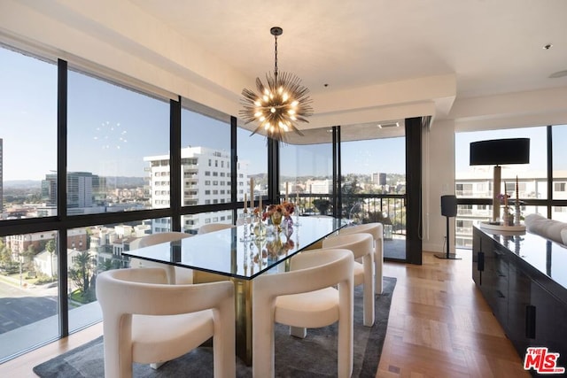 dining space with parquet flooring, a wealth of natural light, a wall of windows, and a chandelier