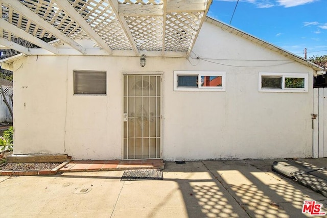 doorway to property with a pergola and a patio