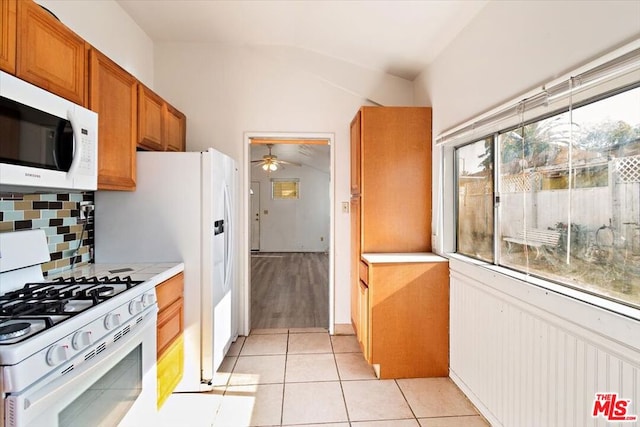 kitchen with ceiling fan, backsplash, light tile patterned floors, white appliances, and lofted ceiling