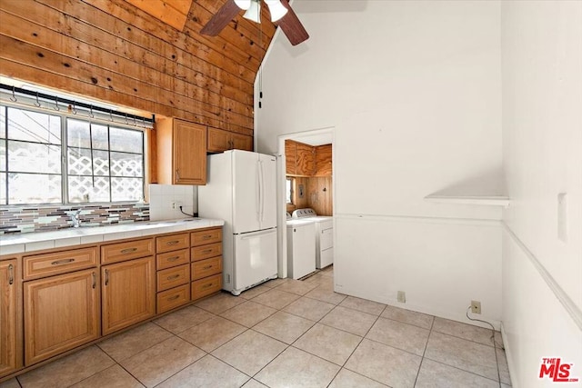 kitchen with washer and dryer, light tile patterned flooring, white fridge, decorative backsplash, and tile counters