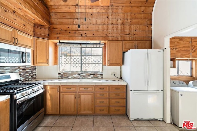 kitchen featuring tasteful backsplash, light tile patterned floors, separate washer and dryer, stainless steel appliances, and tile countertops