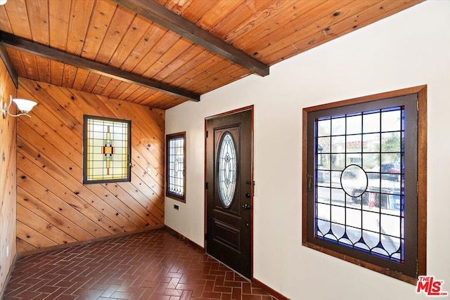 entrance foyer with beamed ceiling, wooden walls, and wooden ceiling