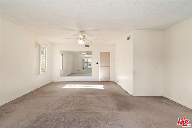 carpeted spare room with ceiling fan and a textured ceiling