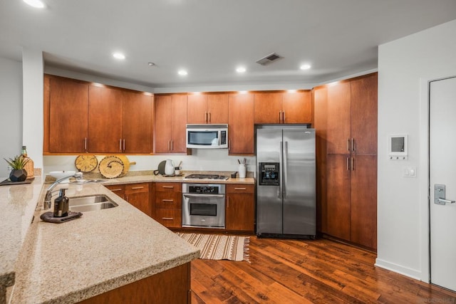 kitchen featuring sink, dark hardwood / wood-style floors, light stone countertops, and stainless steel appliances