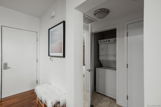 hall with hardwood / wood-style floors and stacked washing maching and dryer