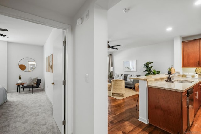 kitchen with sink, ceiling fan, kitchen peninsula, and light stone countertops