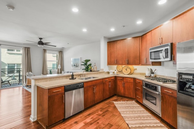 kitchen featuring kitchen peninsula, appliances with stainless steel finishes, sink, light stone countertops, and dark hardwood / wood-style floors