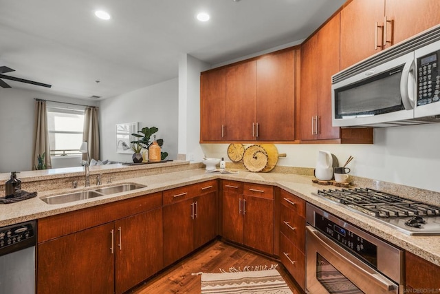 kitchen with sink, stainless steel appliances, kitchen peninsula, and dark hardwood / wood-style flooring