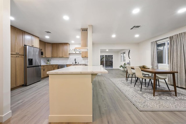 kitchen featuring tasteful backsplash, sink, light wood-type flooring, and appliances with stainless steel finishes