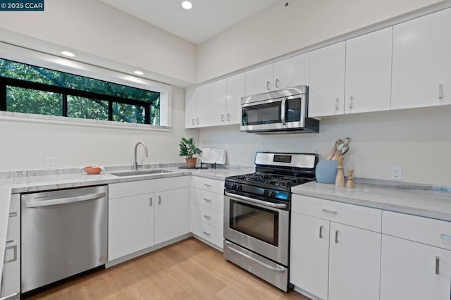 kitchen featuring sink, white cabinetry, appliances with stainless steel finishes, and light wood-type flooring