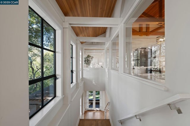 stairway with wooden ceiling, a healthy amount of sunlight, and beam ceiling