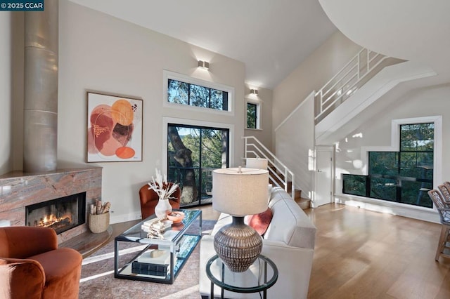 living room featuring a fireplace, hardwood / wood-style floors, and a towering ceiling