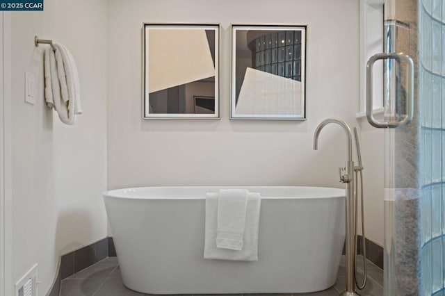 bathroom with a tub to relax in and tile patterned floors