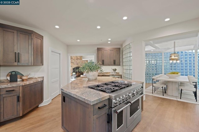 kitchen featuring decorative light fixtures, double oven range, light hardwood / wood-style flooring, and a kitchen island