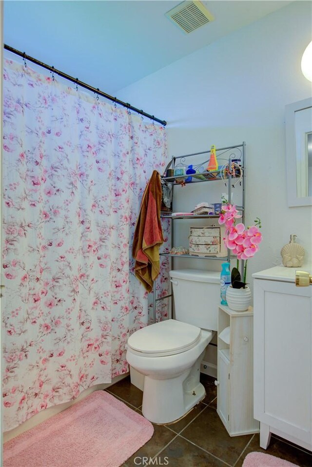 bathroom featuring curtained shower, toilet, and tile patterned floors