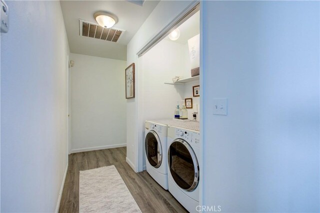 laundry room with light hardwood / wood-style floors and washer and dryer