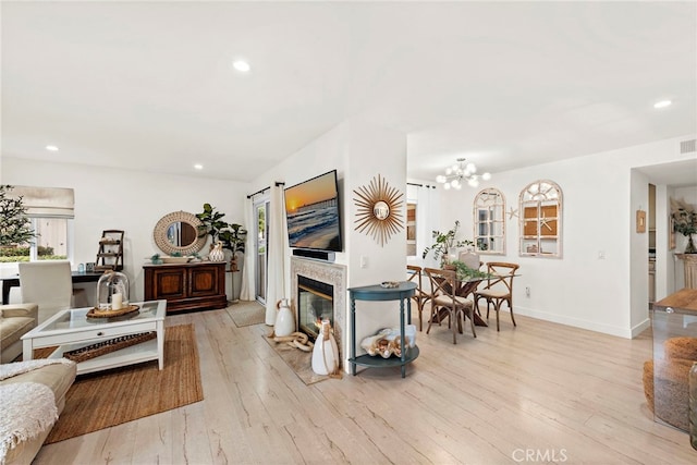 living room with a notable chandelier, a fireplace, and light hardwood / wood-style floors