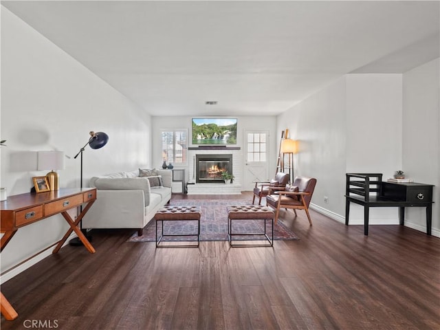 living room with a brick fireplace and dark hardwood / wood-style flooring