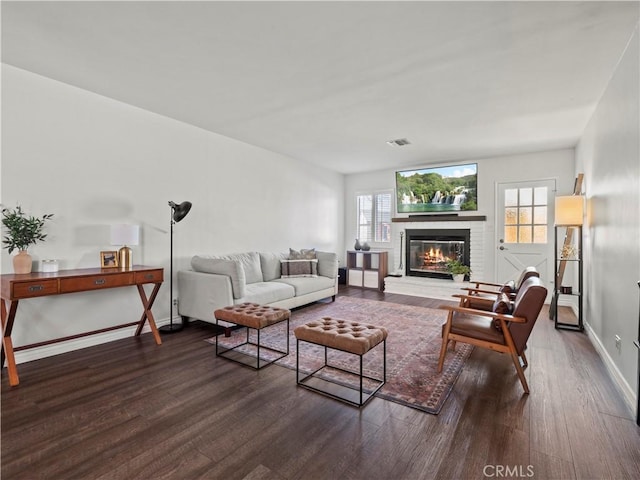 living room featuring dark wood-type flooring and a fireplace