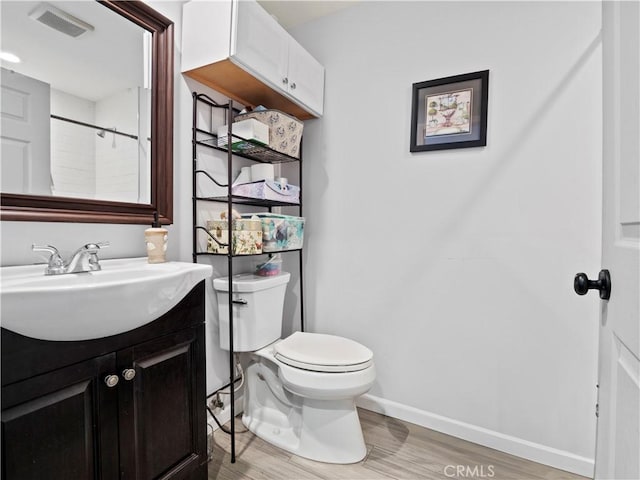 bathroom featuring vanity, hardwood / wood-style flooring, a shower, and toilet