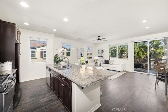 kitchen with dark brown cabinetry, sink, dark hardwood / wood-style flooring, an island with sink, and stainless steel appliances